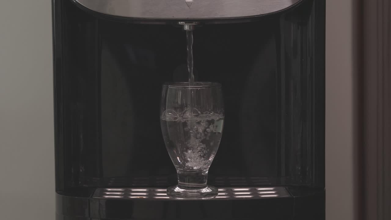 Homme remplissant un verre d'eau claire dans une auge rustique — moment domestique serein, concept d'eau potable pure.
