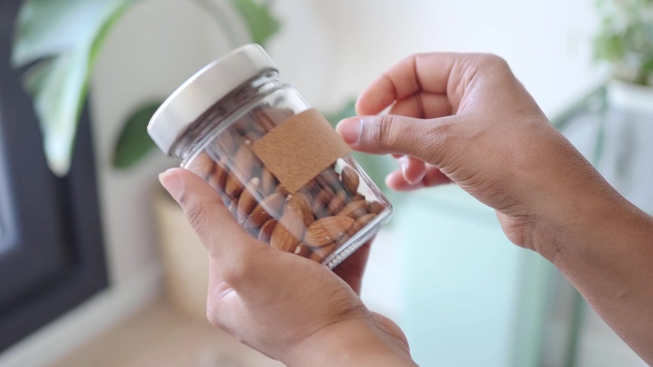 Person Holding a Glass Jar Filled with Almonds