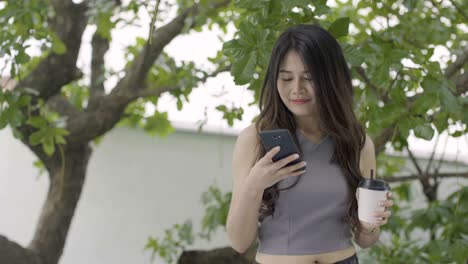 asian women playing phone and drinking hot coffee in coffee shop.