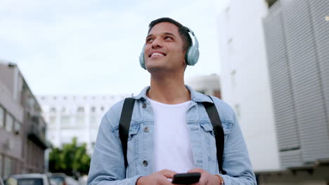 feliz, auriculares y teléfono de un hombre en la ciudad