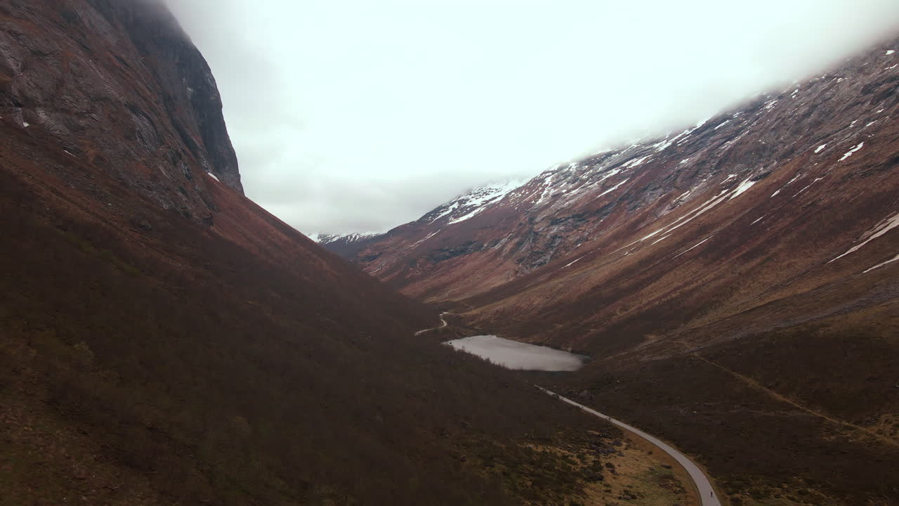 Drone flying through a Norangsdalen in Norway. The sky is covered with clouds and the mountains look majestic.