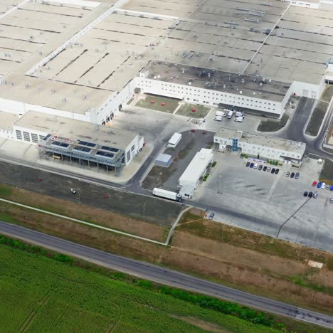 huge industry near green field. roofs of industrial buildings of a modern factory with car parking in summer. top aeriel view