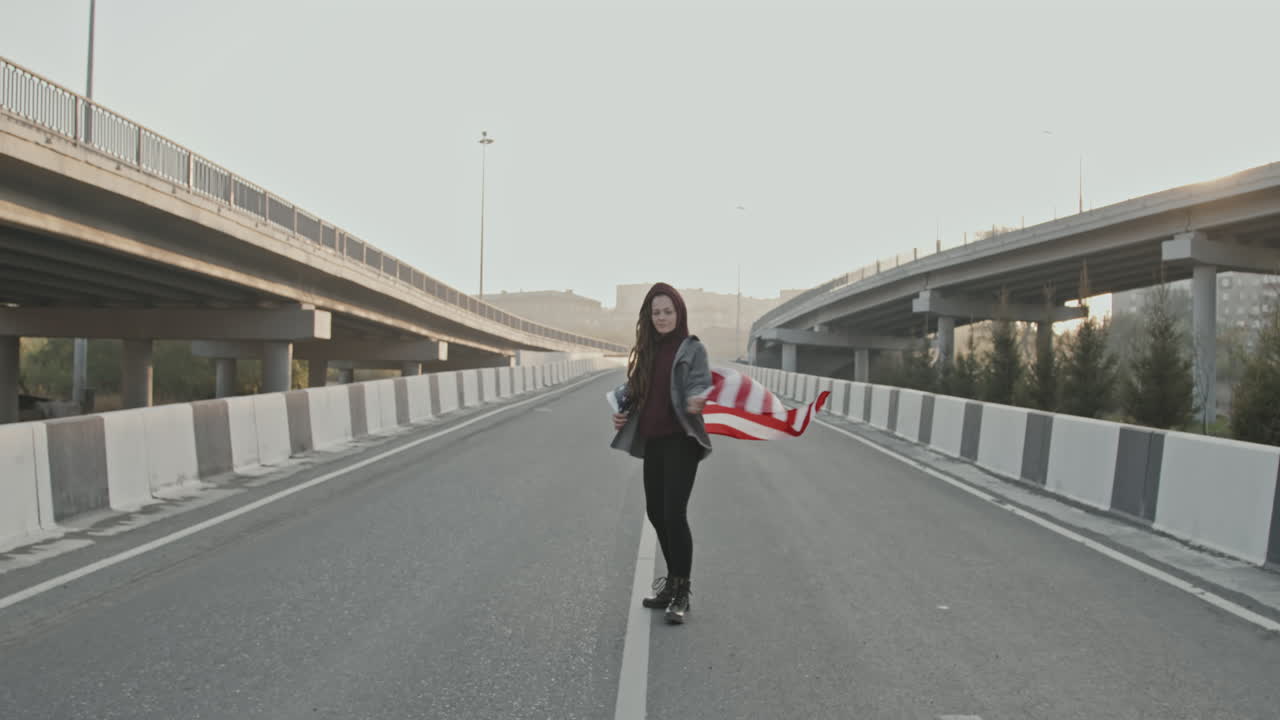 Woman walking on highway with American flag