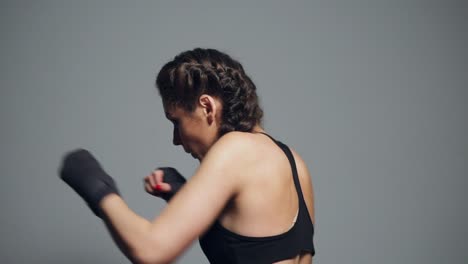 Junge-Frau-Trainiert-Mit-In-Boxbänder-Gehüllten-Händen,-Isoliert-Auf-Grauem-Hintergrund