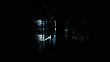 man walks along a dark long corridor. abandoned building, dark corridor, dark silhouette of a man, light in the doorway, ruins, broken windows, rust, unfinished