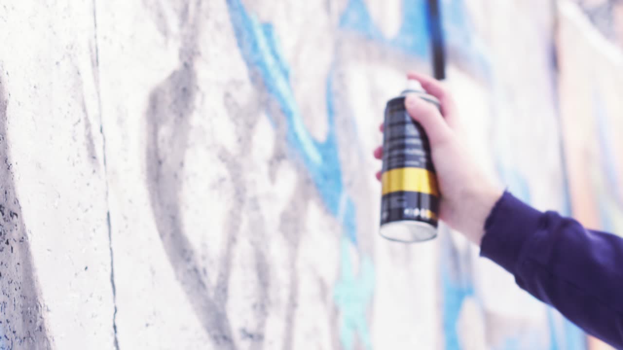 artista de graffiti pintando con spray una pared