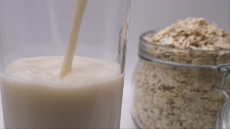 non dairy milk alternative pouring a glass of oat milk