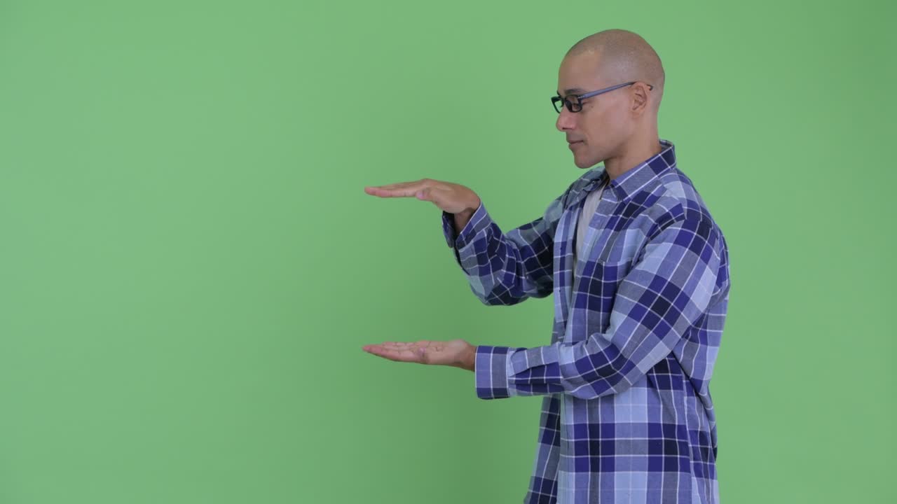 Happy handsome bald hipster man showing something