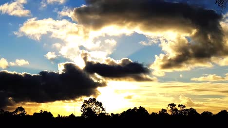 Langsamer-Schwenk-Hyperlapse-Eines-Goldenen,-Wolkigen-Sonnenuntergangs-Vor-Einer-Ländlichen-Skyline