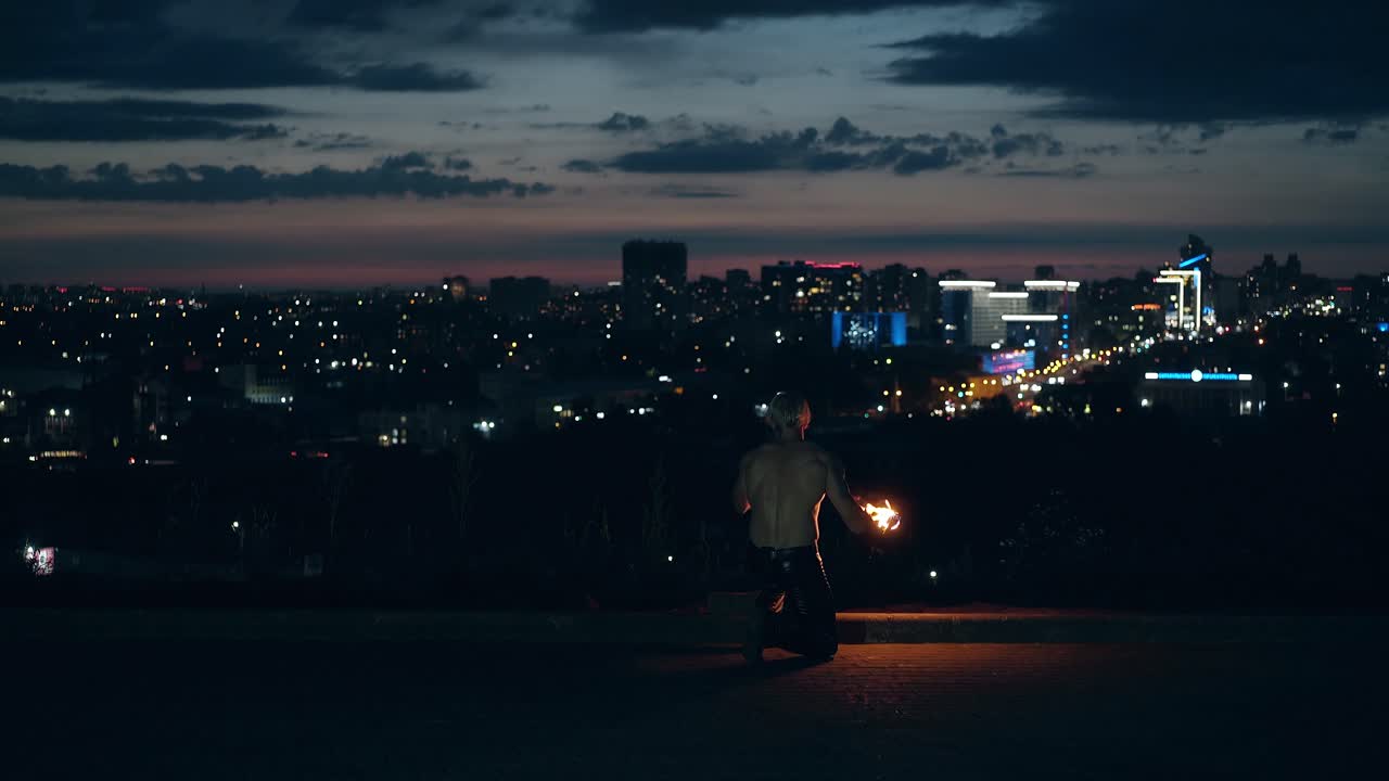 젊은 금발 남자가 불로 트릭을 합니다. 남자의 얼굴은 카메라로 불을  ⁇ 습니다. 무 ⁇ 을  ⁇ 고 병에서 연료를 마시죠.