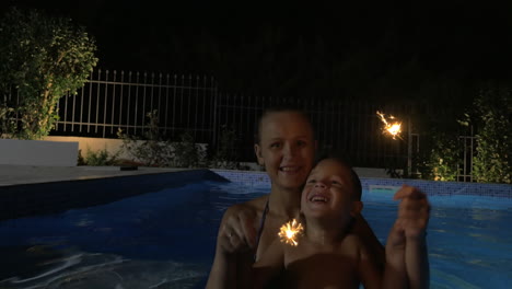 woman and boy with sparklers in pool