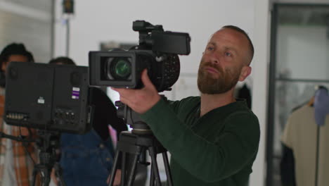 male film camera operator looking through eyepiece shooting movie or video in studio