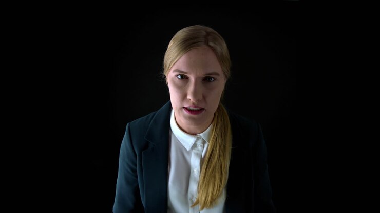 An angry woman manager on a black background yells at an employee for his inefficiency