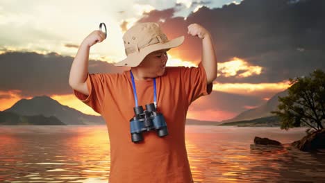 asian boy with a hat and binoculars using the magnifying glass then flexing his bicep at a lake. boy researcher examines something, travel tourism adventure concept