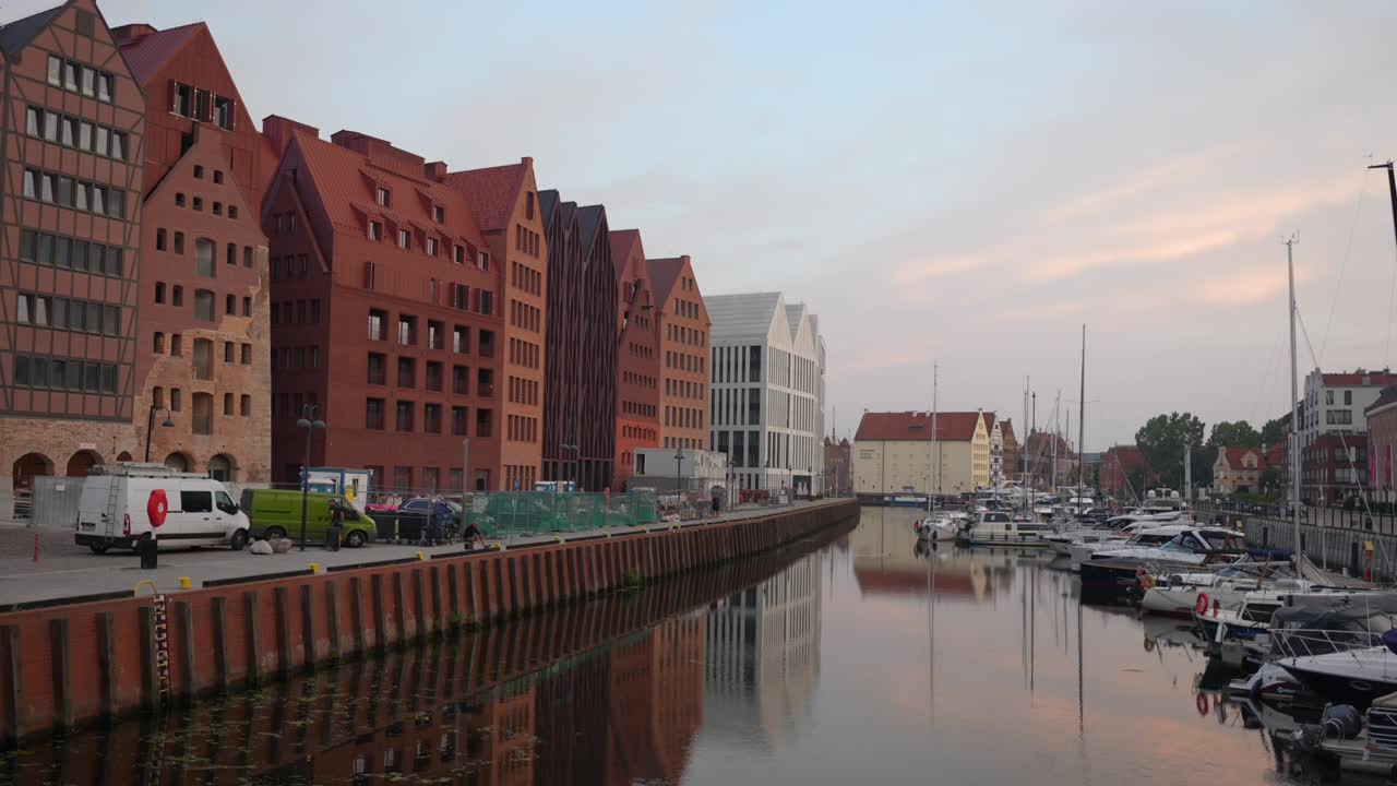 Apartments along Motlawa river in Gdansk. Canal with boats on a calm morning
