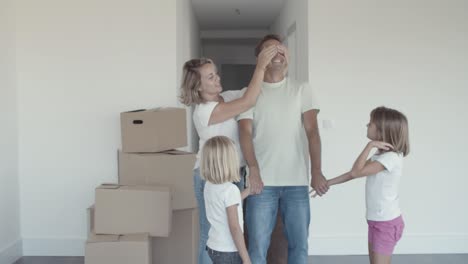 two cheerful girls and their mom leading dad with closed eyes