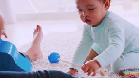 Schwarzer-Kleinkindjunge-Spielt-Xylophon-Mit-Mama-Im-Wohnzimmer