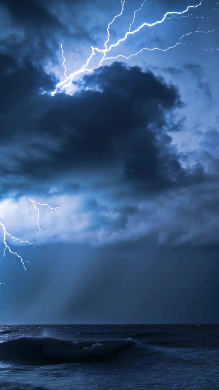 Video verticale: Nuvola lampeggiante che scaglia fulmini sul mare dopo un lampo a sinistra, illuminando le onde