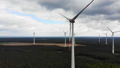 Drone-shot-of-European-windmill-spinning-in-the-middle-of-a-green-field-in-Saarland,-Germany