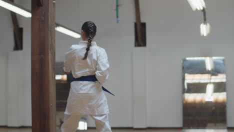 tracking shot of karateka practicing kick jumps in gym