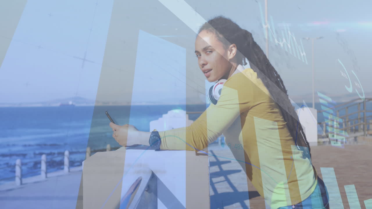 Animation of statistics and graphs over woman using smartphone on promenade by the sea