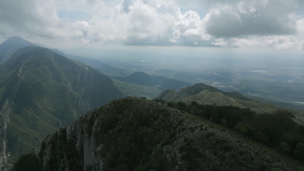 Aerial view over Maja Gamtitit summit in Albania with dramatic clouds and distant river landscape