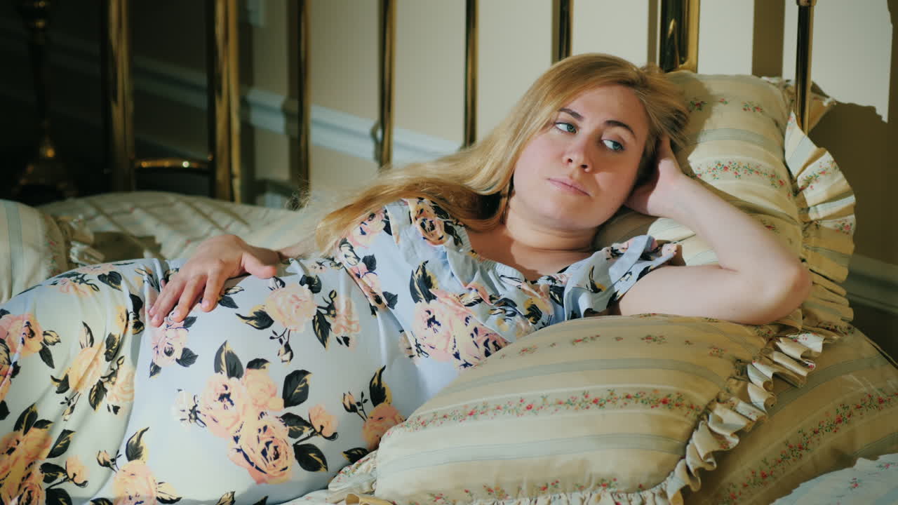 Donna incinta pensierosa sdraiata nel suo letto.