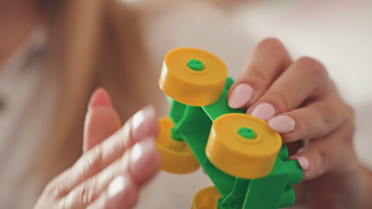 La mamma coinvolge il figlio con una piccola macchina colorata. Scena familiare al chiuso con madre e figlio che giocano insieme. Una madre caucasica condivide un momento ludico-educativo con il figlio usando una vivace macchinina giocattolo.