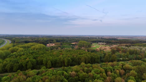 expansive green forest landscape view. lush green forest stretches across the horizon under a clear blue sky. rolling hills and a highway are visible nearby