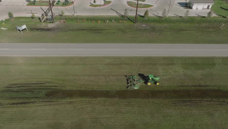 a 4k aerial drone view captures a heavy equipment operator driving a tractor with a brush hog mower attachment, mowing the median of fairmont parkway on a sunny morning in la porte, texas.