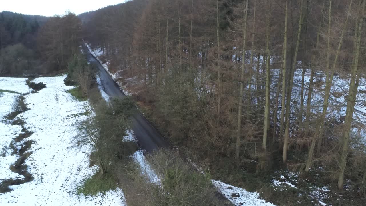 Sneklædt walisisk skovområde ved Moel Famau vinterlandskab, luftfoto med stigende afsløring af vej