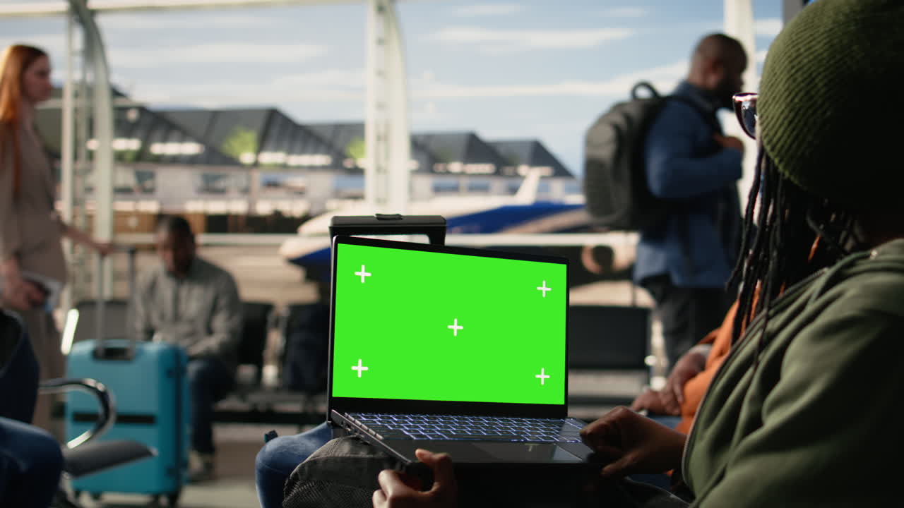 Mockup con schermo verde, persone in una sala d'attesa dell'aeroporto, informazioni di viaggio sul tabellone.