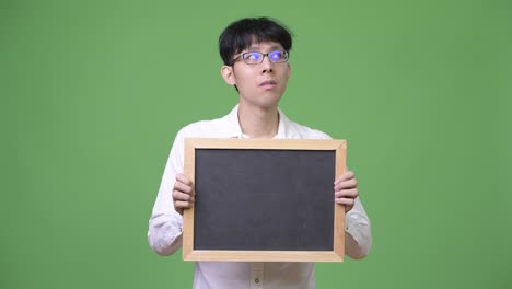 생각 하는 동안 검은판 을 들고 있는 젊은 아시아인 사업가