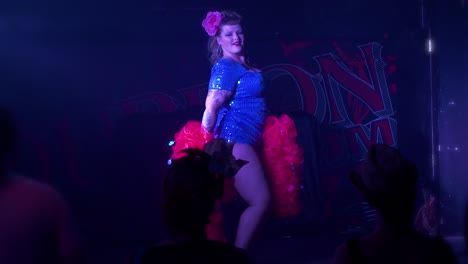 curvy burlesque dancer shakes her hips on stage with a red feather boa during a sexy live performance