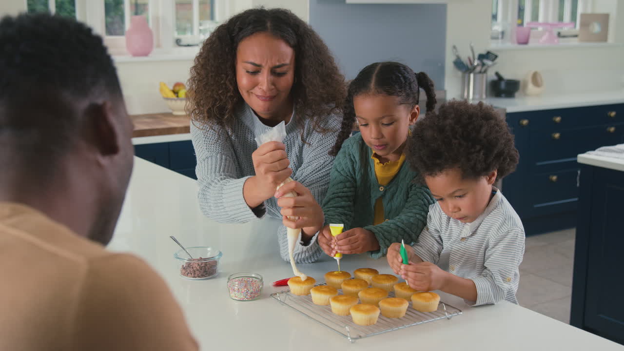 familia con niños en la cocina decorando pastelitos juntos
