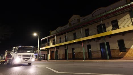 vehicles passing by old colonial buildings at night