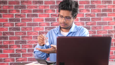 hombre desinfectando las manos mientras trabaja en la computadora portátil