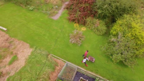 imágenes de drones de un jardinero empujando una carretilla
