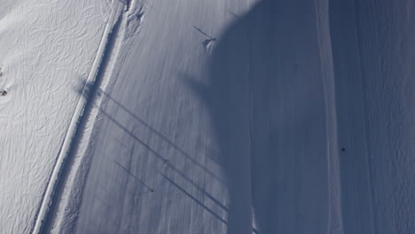 aerial birds eye shot following skier on snowy white slope in alp mountains