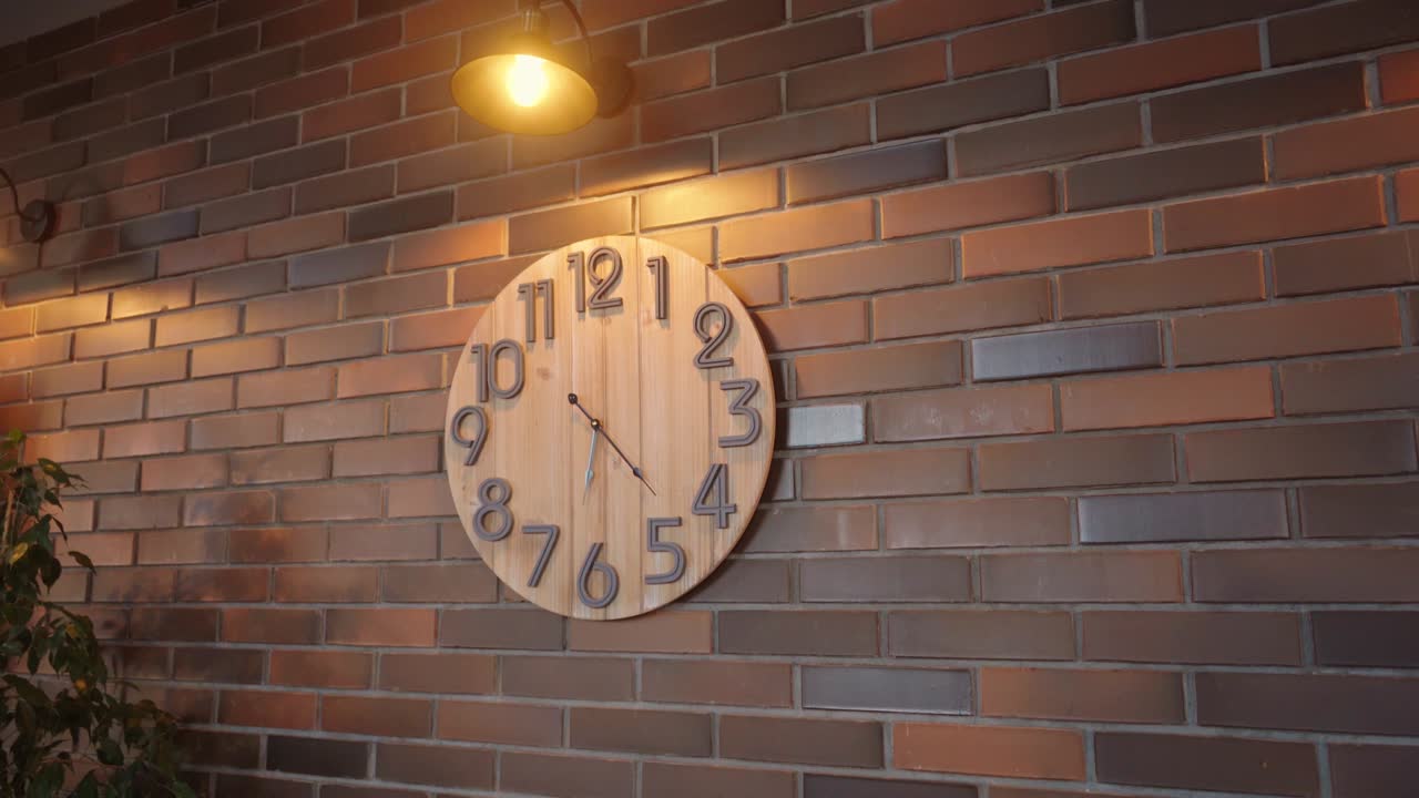 A wooden clock on a brick wall in close-up