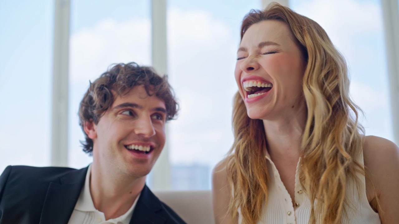 Couple browsing photo album laughing sofa. Close up man pointing book pages.