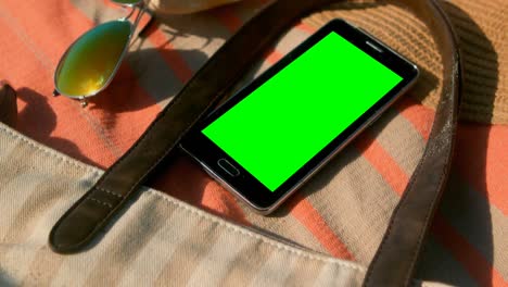 Teléfono-Móvil-Y-Accesorios-Sobre-Una-Manta-De-Picnic-En-La-Playa-En-Un-Día-Soleado-4k