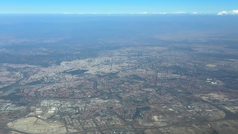 an elevated aerial view taken from a plane cockpit of madrid city in a hazy summer morning under a splendid blue sky