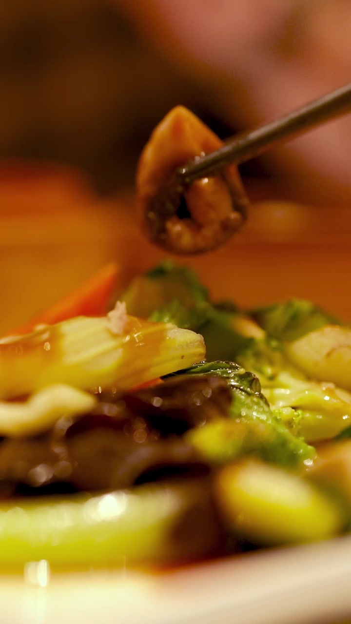 Bacchette sollevano con grazia verdure saltate in padella in un ambiente di ristorante caldo e accogliente con illuminazione soffusa e colori vivaci
