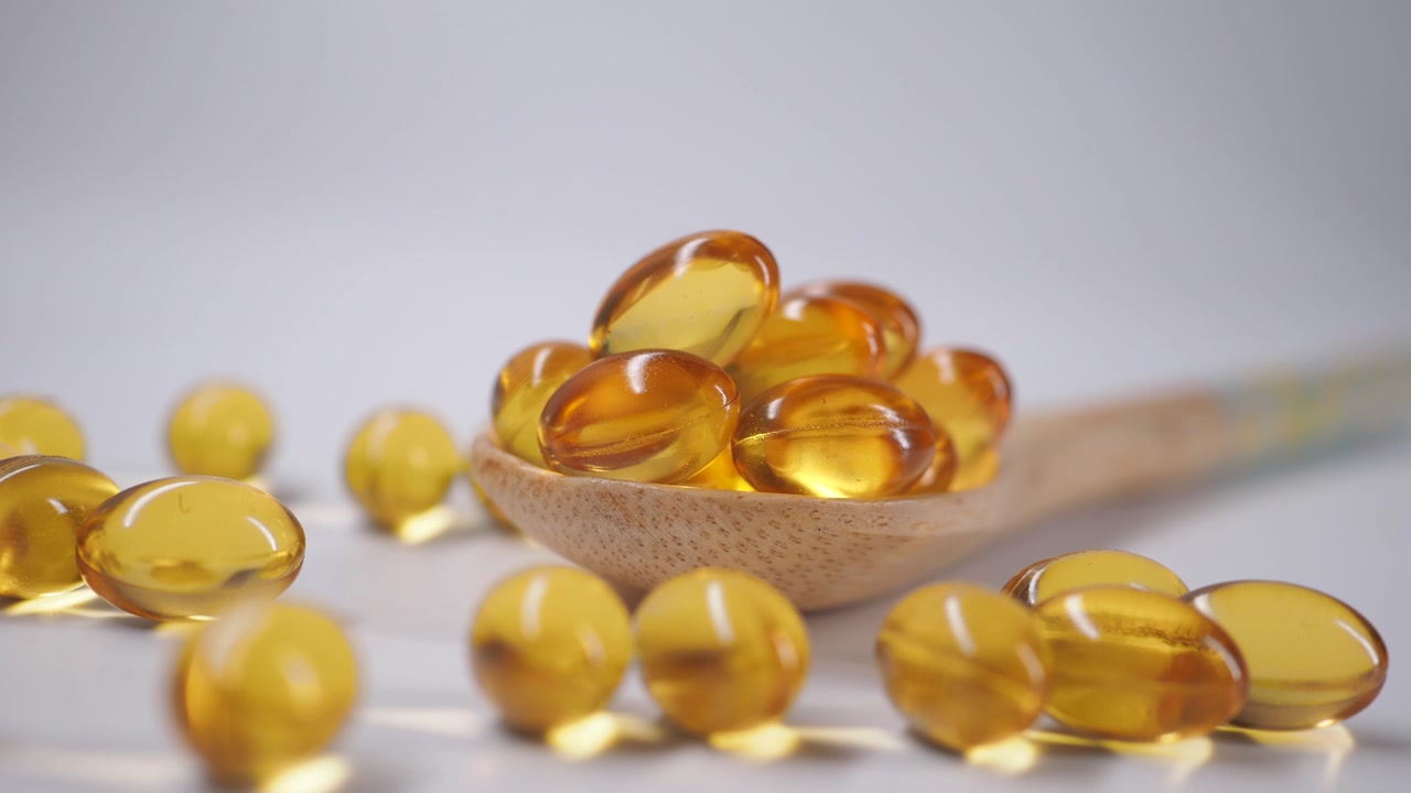 Shiny Yellow Supplement Pills in a Wooden Spoon