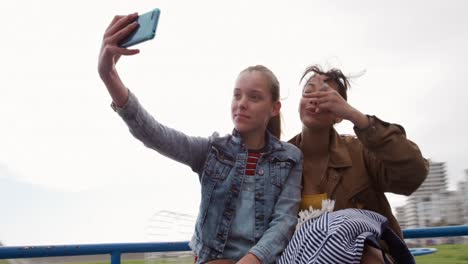 front view of a caucasian and a mixed race girl taking selfie on a merry-go-round