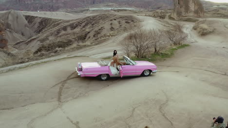 couple in a vintage pink convertible car at cappadocia landscape