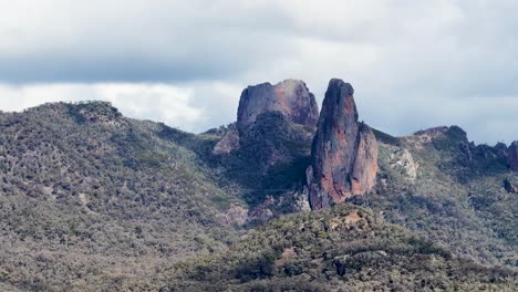 static wide shot of the breadknife rock spire and surrounding forested mountains under cloudy daylight, with no visible camera movement or human presence