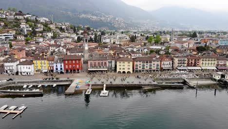 Luftüberführung-Mit-Einer-Drehung-Vom-Lago-Maggiore-über-Die-Promenade-Von-Ascona-Im-Tessin,-Schweiz-über-Die-Dächer-Rund-Um-Den-Kirchturm,-Der-Den-See-Und-Die-Berge-Freigibt