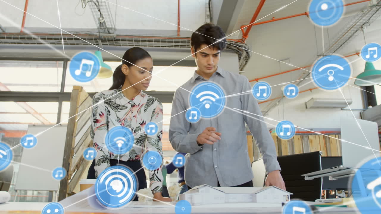 animación de una red de iconos digitales sobre un hombre y una mujer caucásicos discutiendo sobre un modelo en la oficina.